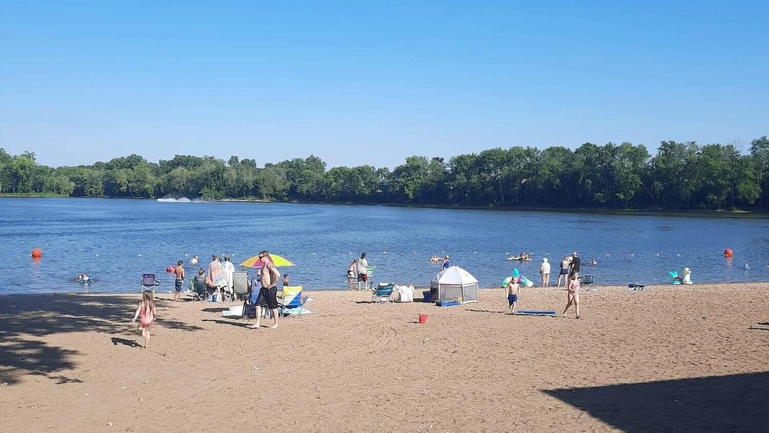 Swimming beach at Lazy L Lake with families enjoying the water